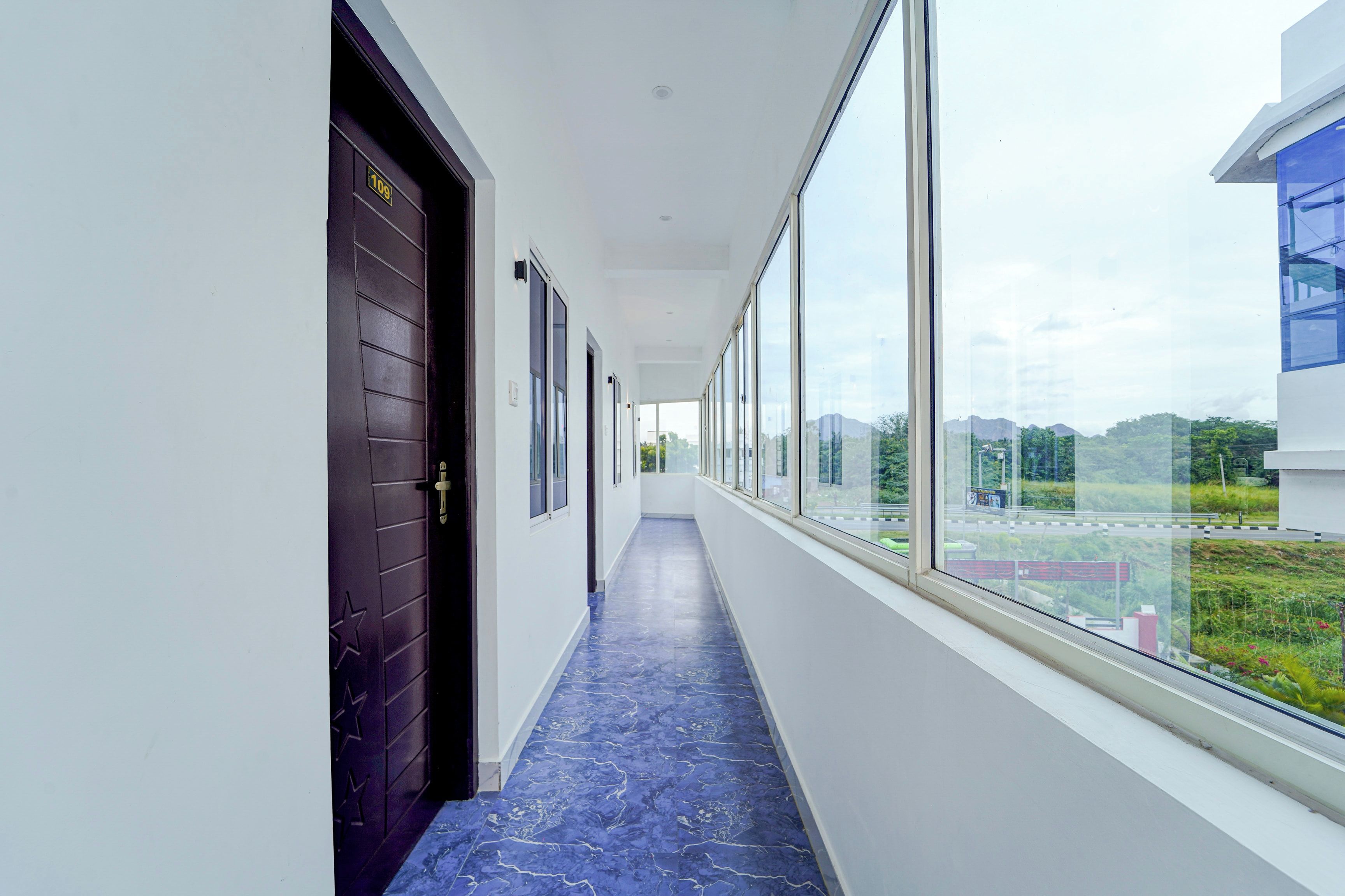 Un pasillo con piso de mármol azul, ventanas amplias y puertas con diseños de estrellas.