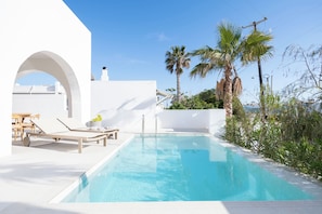 A modern outdoor pool area with a clear blue pool, white walls, and a wooden deck with lounge chairs. - Paros villa with private pool, steps from the sea & traditional village in Aliki (Aliki - Paros)