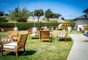Een terras met houten stoelen en tafels, een houten vat en een oldtimer camper.