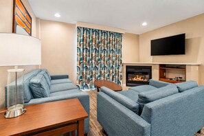 Een moderne woonkamer met een open haard, een flatscreen televisie erboven en een kamerkleed met een patroon.