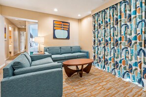 A hotel room with a sofa set, a round coffee table, and a patterned curtain. - 3X3BR Desert Escape Near Coachella & amenities (Palm Springs)