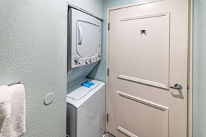 A laundry room with a washing machine and dryer, a towel rack, and a door with a lock. - 3X3BR Desert Escape Near Coachella & amenities (Palm Springs)