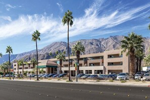 A hotel with multiple floors, a parking lot, and palm trees in front. - 3X3BR Desert Escape Near Coachella & amenities (Palm Springs)