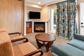 A living room with a fireplace, a flat-screen TV mounted above it, and a sofa. - 2X2BR OasisNearCoachellaw/resort Style-Amenities (Palm Springs)