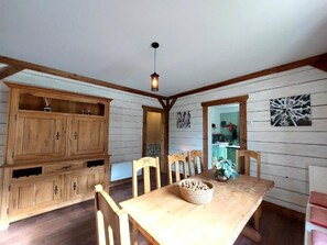 A wooden dining area with a table, chairs, and a hanging light fixture. - Spacious vacation home (sleeps 10) near Gérardmer—ideal for groups and pets (Granges-Aumontzey)