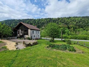 A rustic house with a sloped roof, a wooden porch, and a stone foundation. - Spacious vacation home (sleeps 10) near Gérardmer – ideal for groups and pets (Granges-Aumontzey)