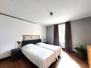 A bedroom with a double bed, a nightstand, a dresser, and a window with curtains. - Spacious vacation home (sleeps 10) near Gérardmer—ideal for groups and pets (Granges-Aumontzey)