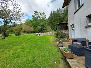 A residential property with a well-maintained lawn, outdoor seating area, and a stone wall. - Spacious vacation home (sleeps 10) near Gérardmer – ideal for groups and pets (Granges-Aumontzey)