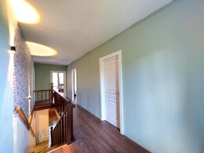 A hallway with a wooden staircase, a white door, and a light green wall. - Spacious vacation home (sleeps 10) near Gérardmer—ideal for groups and pets (Granges-Aumontzey)