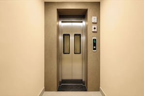 An elevator with a metallic finish, a control panel with a digital display, and a wall-mounted intercom system. - Townhouse GT Road Dadri (Dadri)