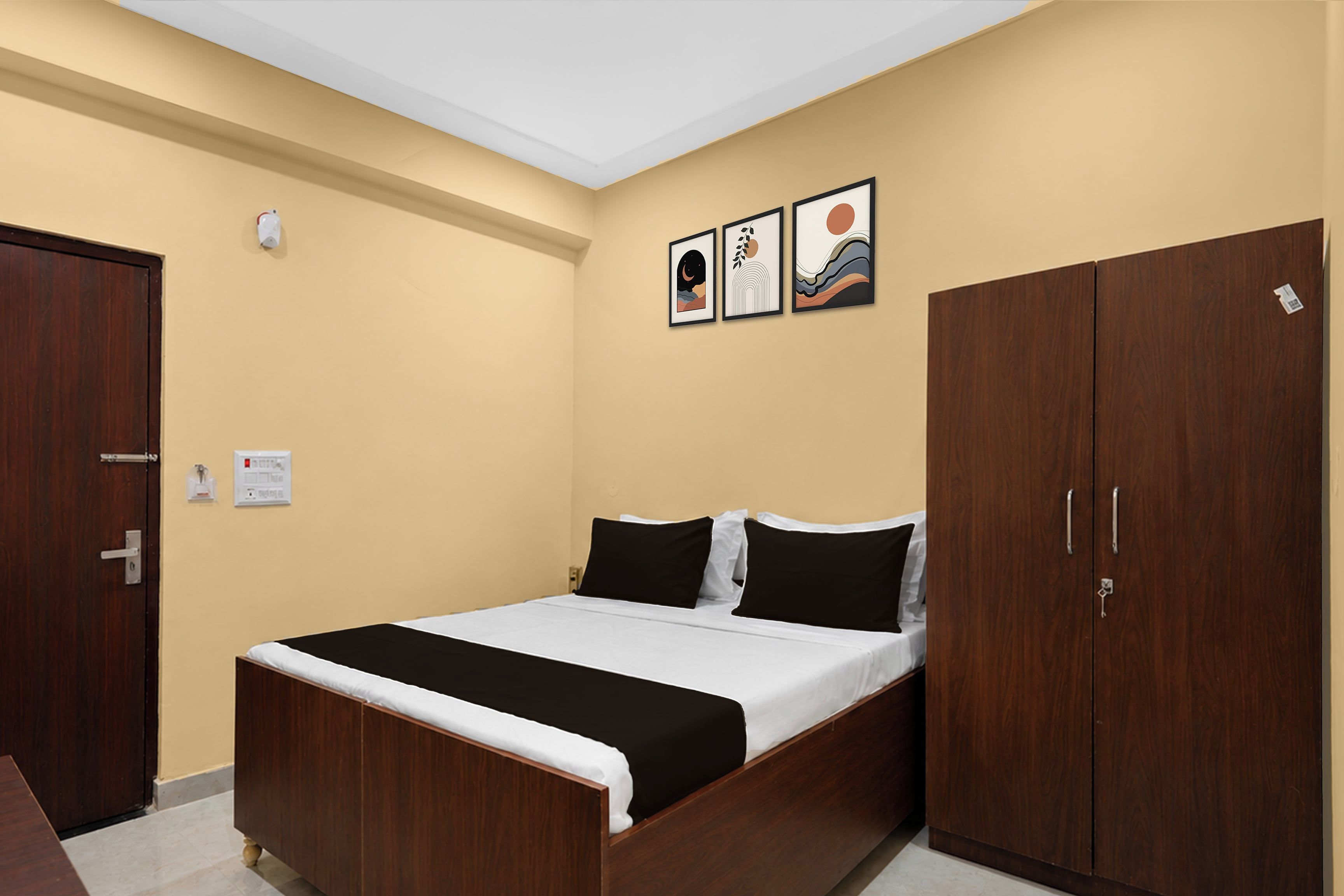 A bedroom with a bed, a wardrobe, and two wall-mounted pictures.