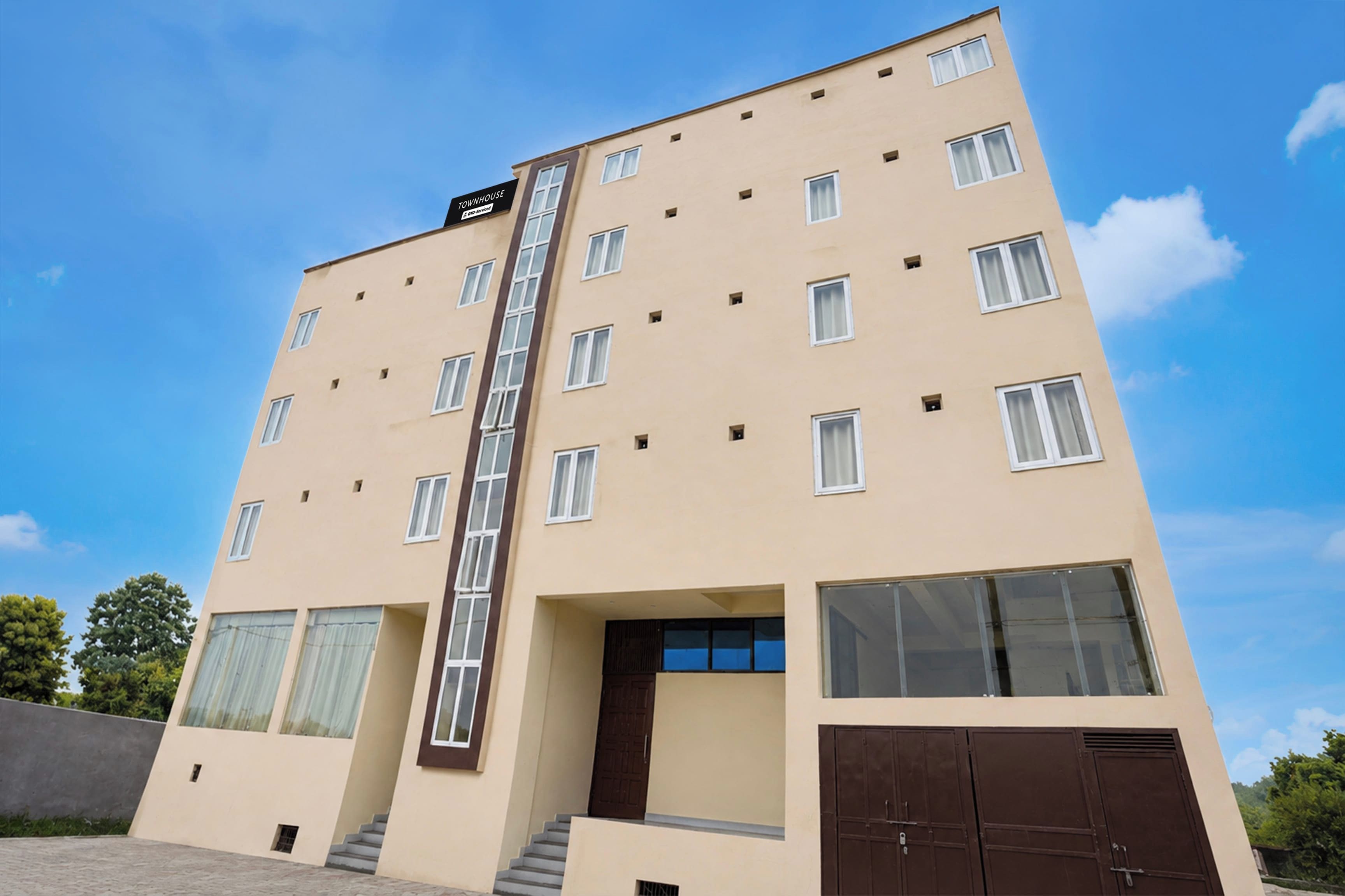 A multi-story hotel building with a central staircase, large windows, and a flat facade.