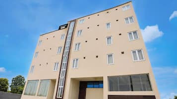 A multi-story hotel building with a central staircase, large windows, and a flat facade.
