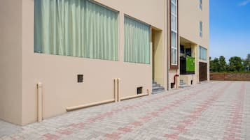 Um edifício com grandes janelas, entrada coberta e calçada pavimentada.
