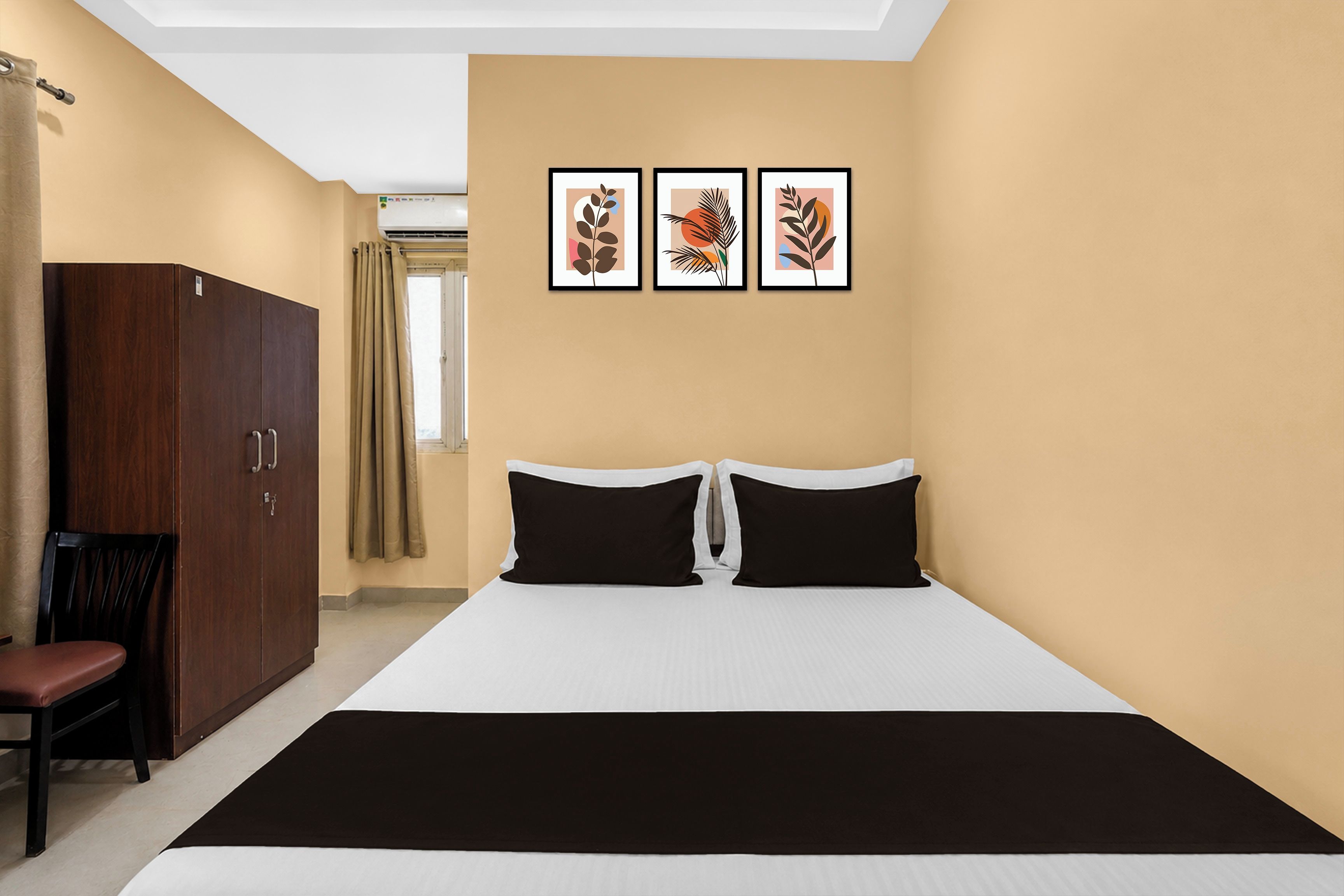 Una habitación de hotel con una cama, un armario, una silla y tres cuadros en la pared.