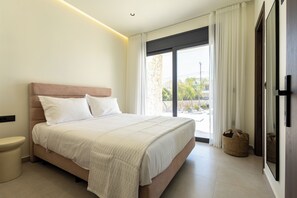 Ein Schlafzimmer mit Bett, Nachttisch, einem Fenster mit Vorhängen und Blick ins Freie.