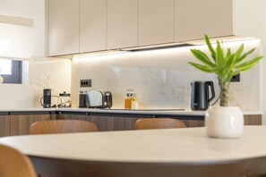 Eine moderne Küche mit einer Marmorarbeitsplatte, einer Kaffeemaschine, einem Toaster und einer Pflanze auf dem Tisch.
