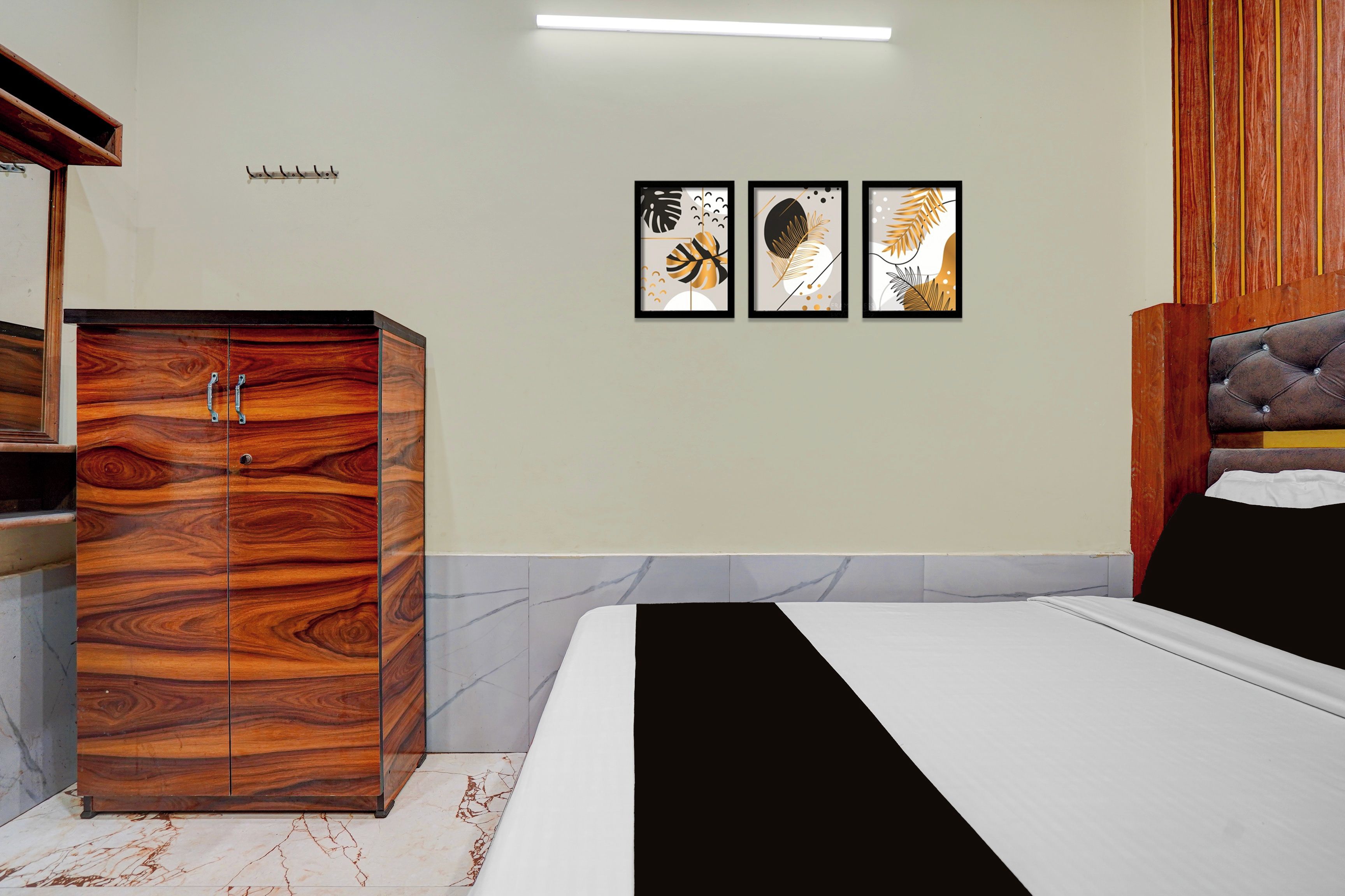 Une chambre à coucher comprenant un lit, une armoire et trois œuvres d’art encadrées accrochées au mur.