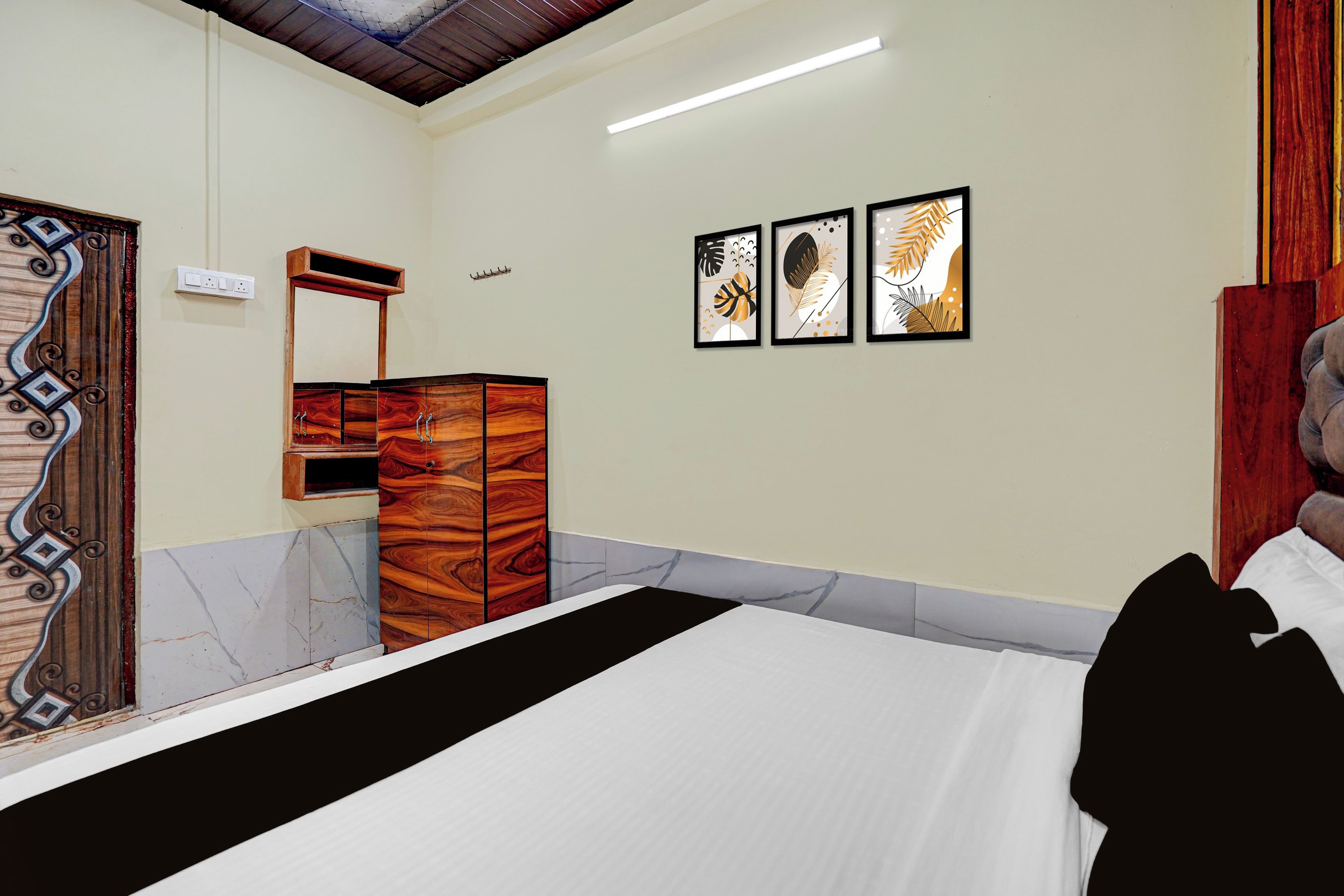 Una camera da letto con un letto, una cassettiera in legno, uno specchio e tre opere d'arte appese alla parete.