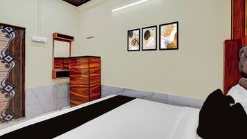 Una camera da letto con un letto, una cassettiera in legno, uno specchio e tre opere d'arte appese alla parete.