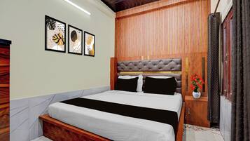 A bedroom with a bed, wooden paneling, a nightstand, a vase with flowers, and framed artwork on the wall.