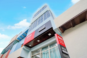 Un hotel con fachada moderna, múltiples ventanales y señalización para habitaciones y servicios.