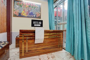 Una recepción de hotel con un cartel que indica que el servicio es proporcionado por OYO.
