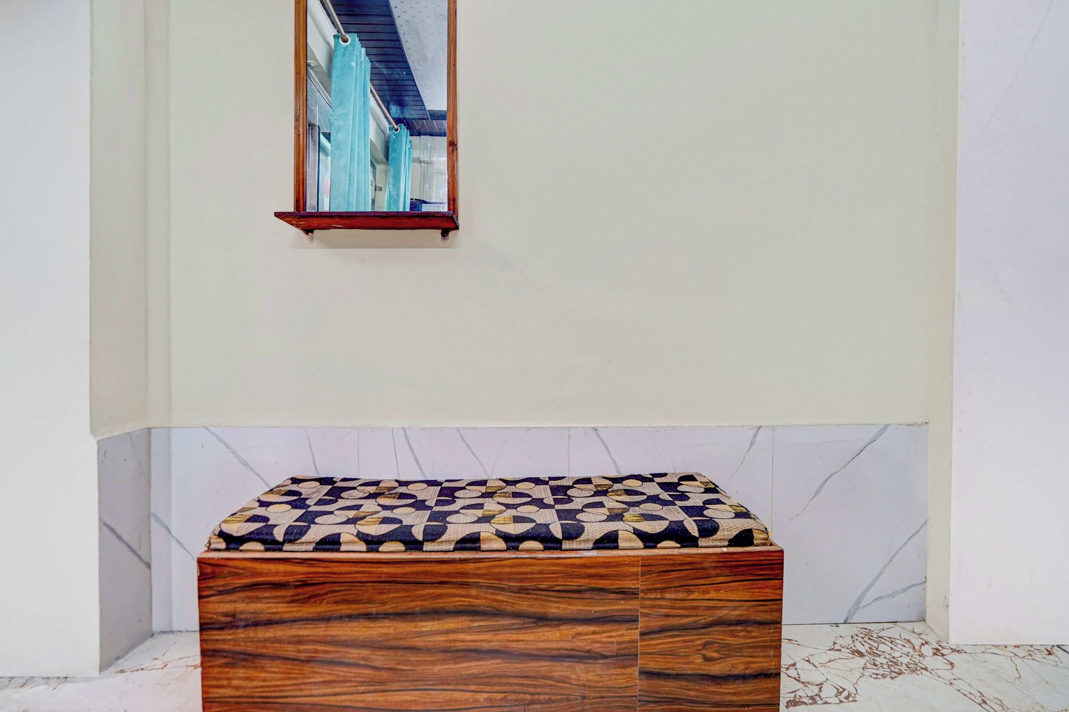 Une salle de bain avec un banc en bois, un miroir et un sol à motifs.