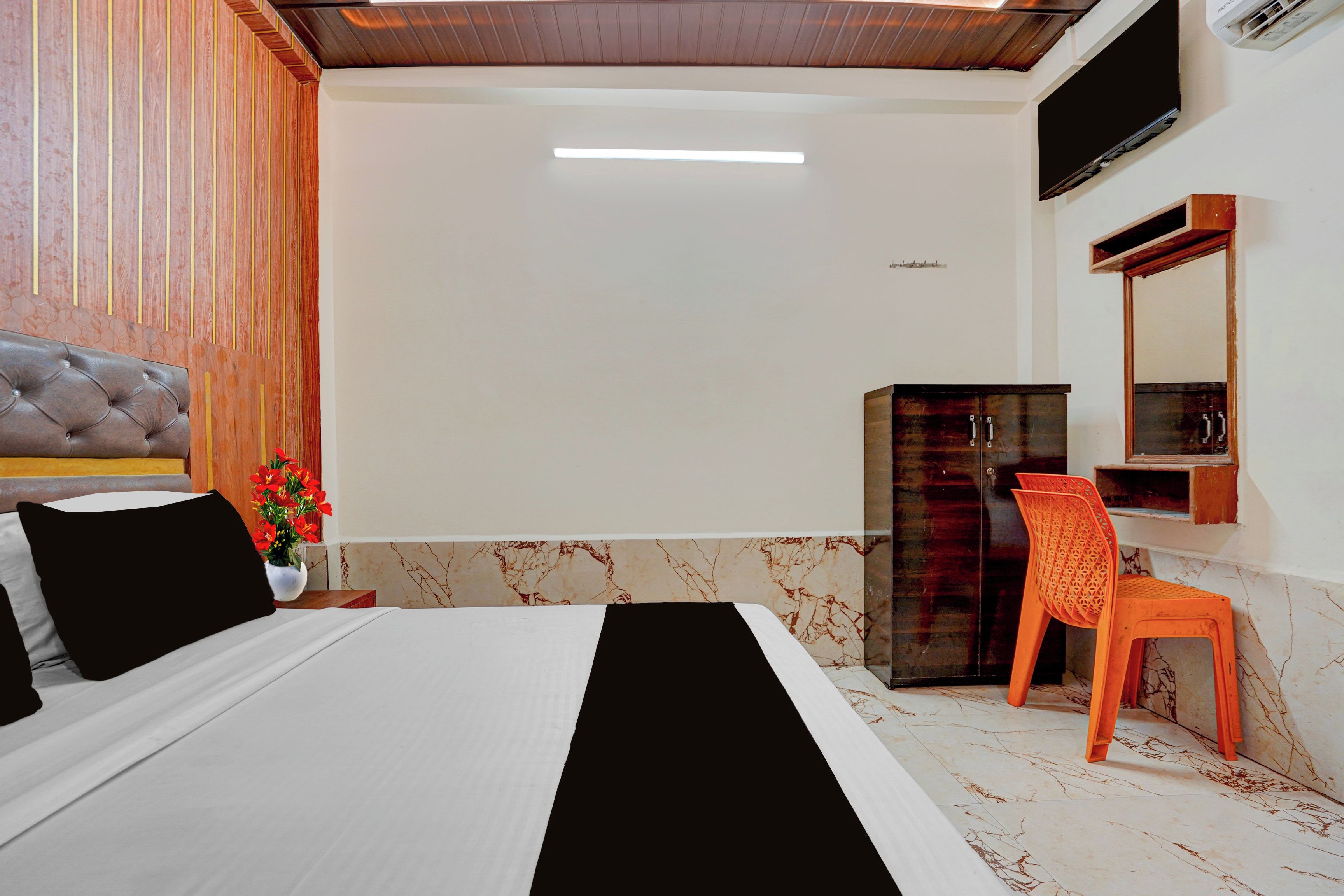 Ein Hotelzimmer mit Bett, Schreibtisch, Stuhl, Kleiderschrank und einem Fernseher an der Wand.