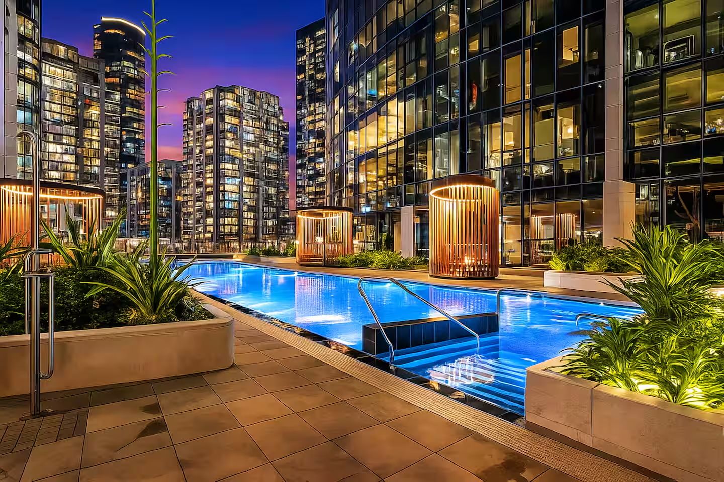 A modern hotel with a swimming pool, surrounded by high-rise buildings.
