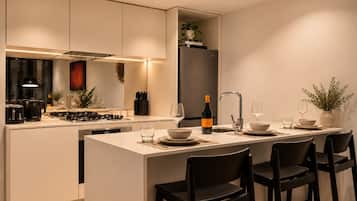 A modern kitchen with a central island, a built-in oven, and a refrigerator.