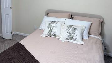 A bedroom with a bed, two pillows, a blanket, and a door.
