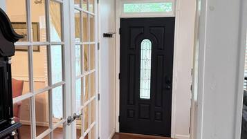 A hallway with a black door, white-framed glass doors, and wooden flooring.