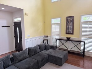 A living room with a sectional sofa, a console table with a bowl, and a door with a window.
