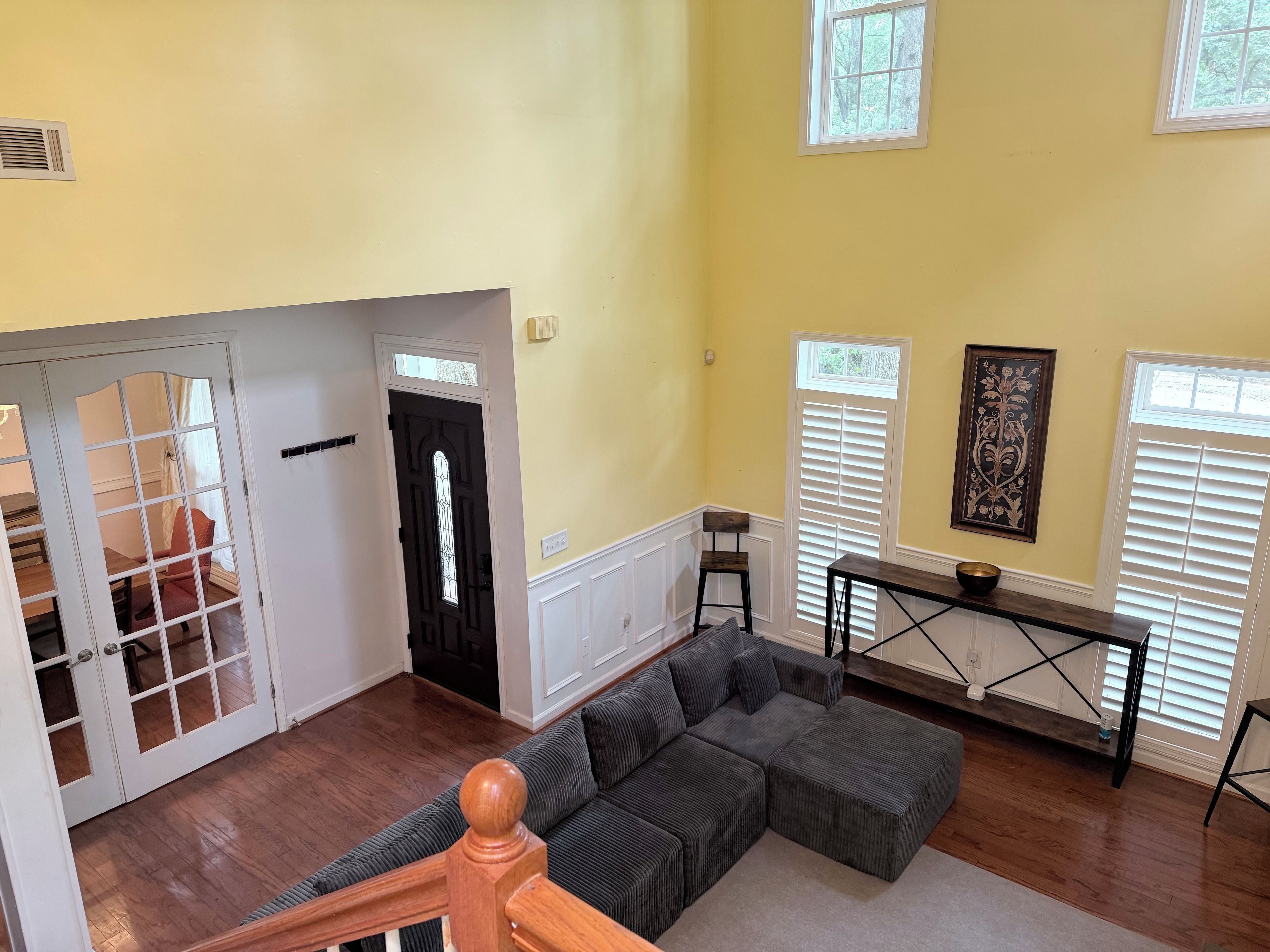A spacious living area with a sectional sofa, a dining table, and a staircase leading to another level.