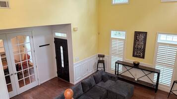 A spacious living area with a sectional sofa, a dining table, and a staircase leading to another level.