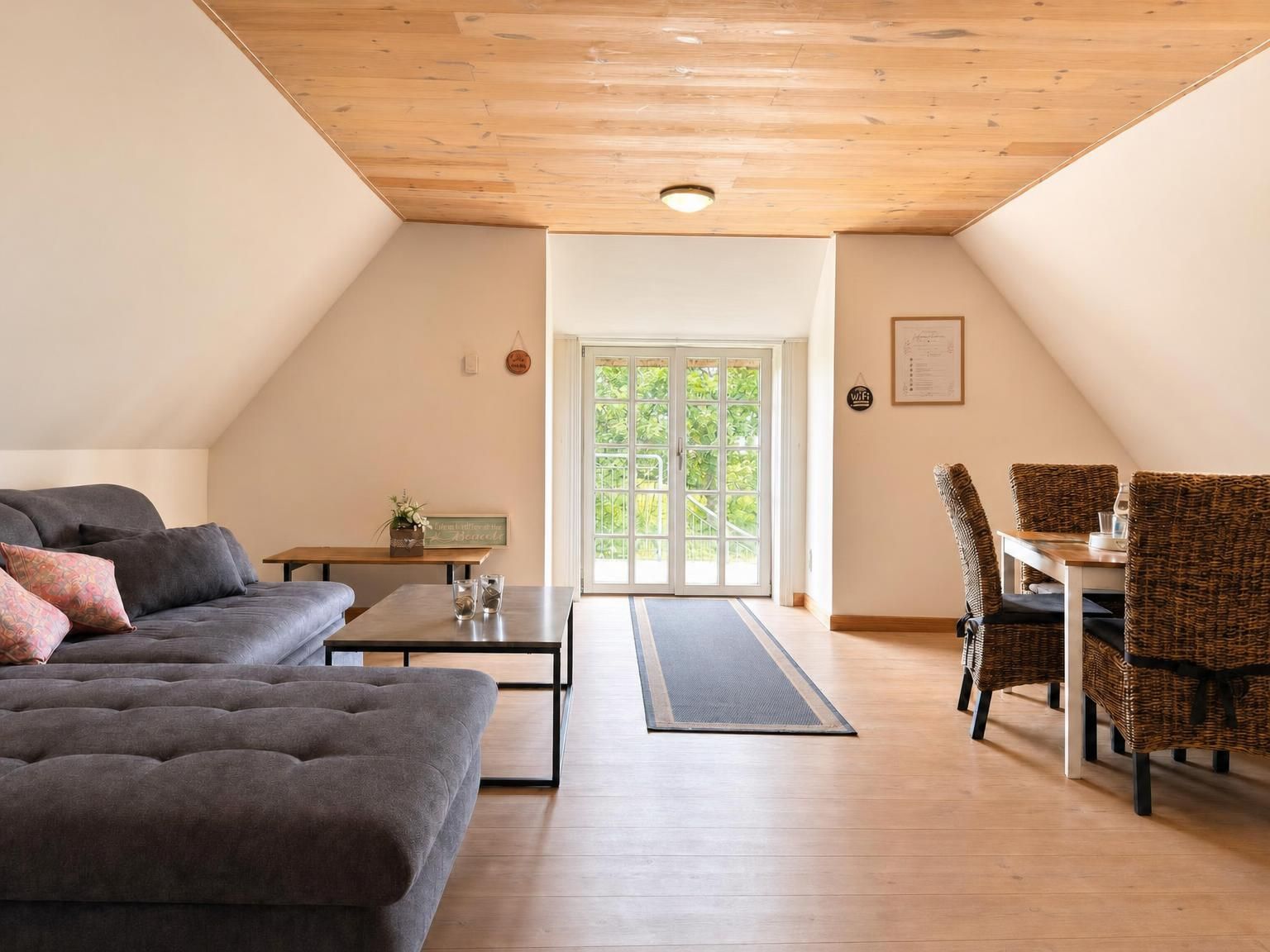 Ein geräumiges Loft mit hohen Decken, einer Couch, einem Esstisch und Korbstühlen.
