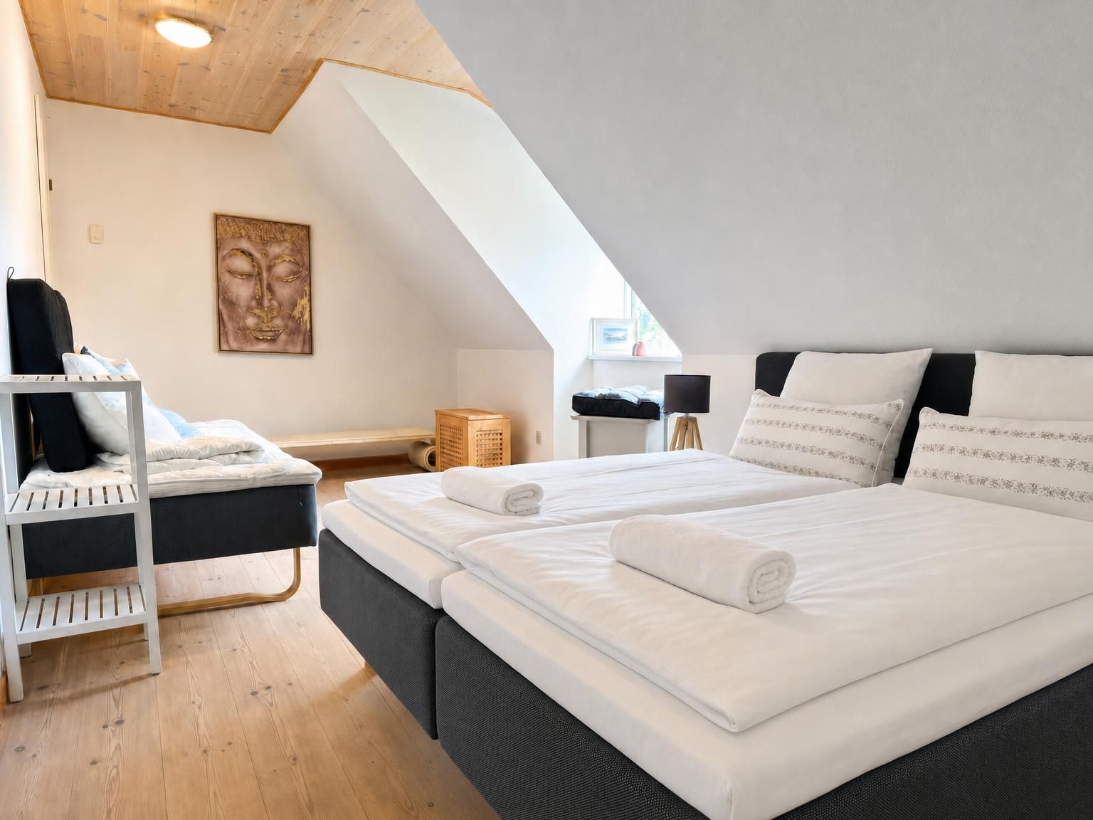 A bedroom with a large bed, a bedside table, a lamp, and a painting on the wall.