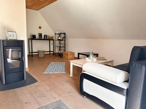 A modern living room with a sofa, a coffee table, a fireplace, and a dining area with a table and chairs.