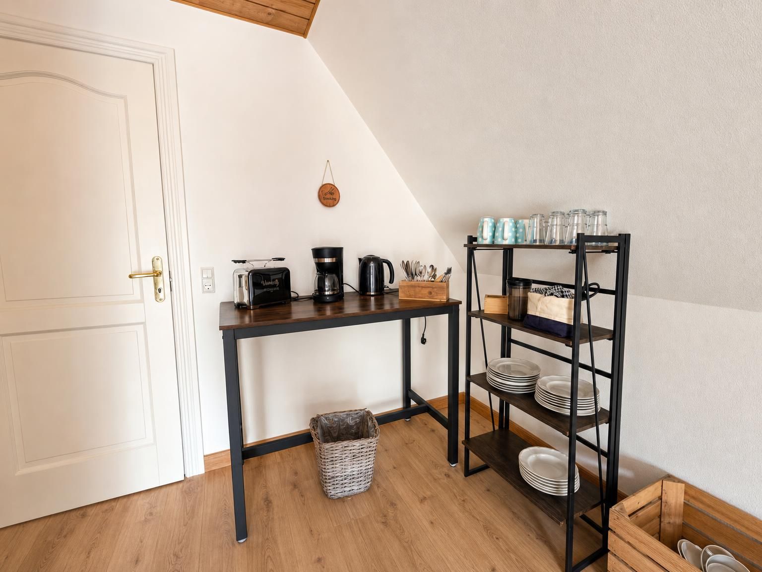 Een kitchenette met een koffiezetapparaat, broodrooster en planken met servies en glazen.