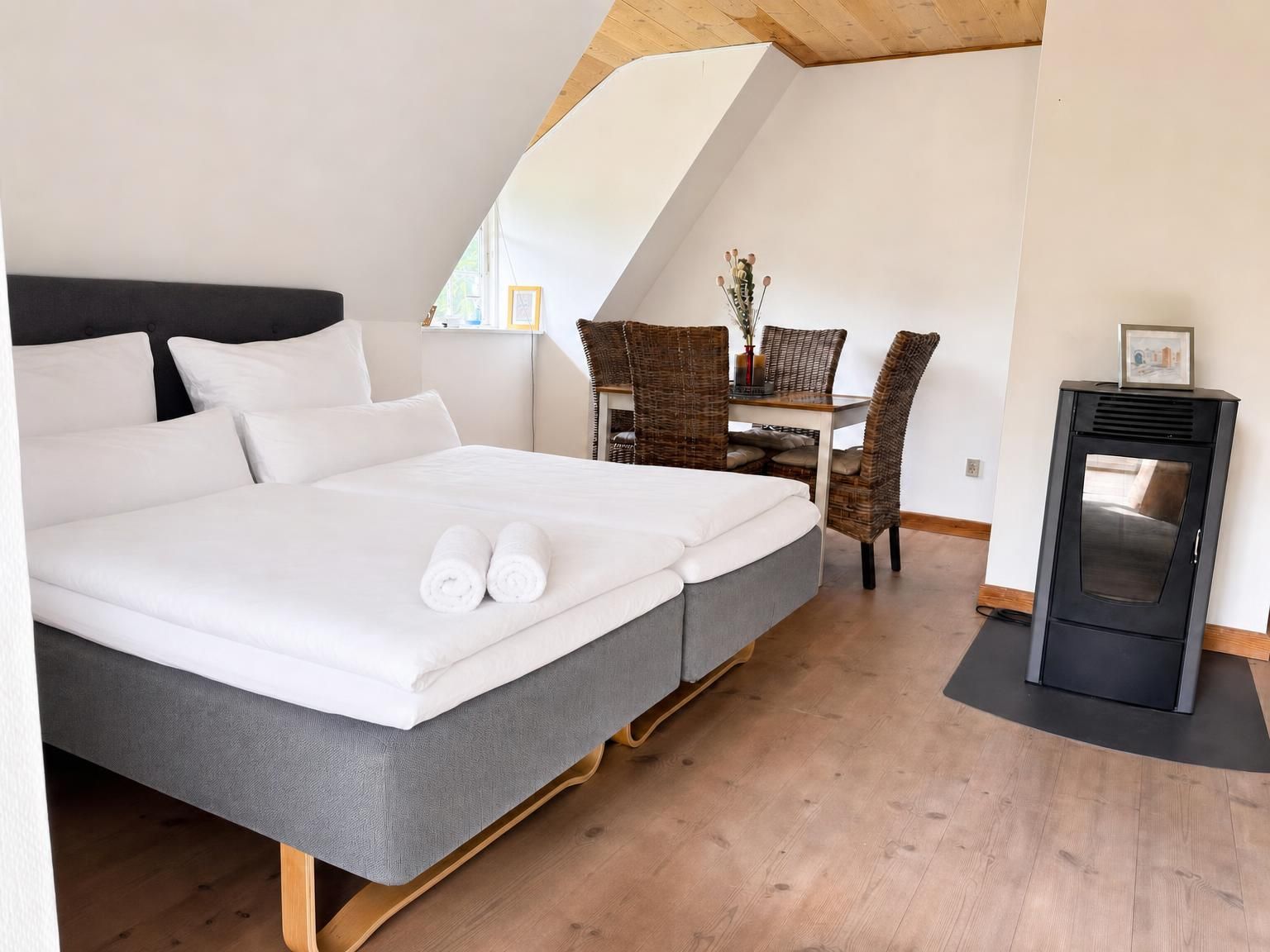 A bedroom with a bed, a desk, and a fireplace.