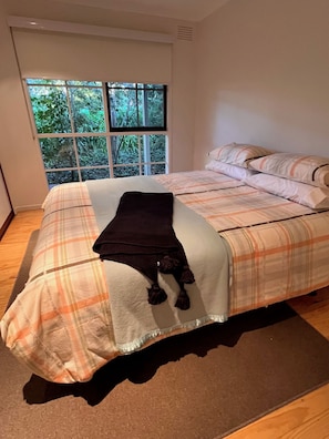 A bedroom with a bed, a window with a view of greenery, and a brown rug. - Close to Warburton walking and bike trail and wineries (Seville)
