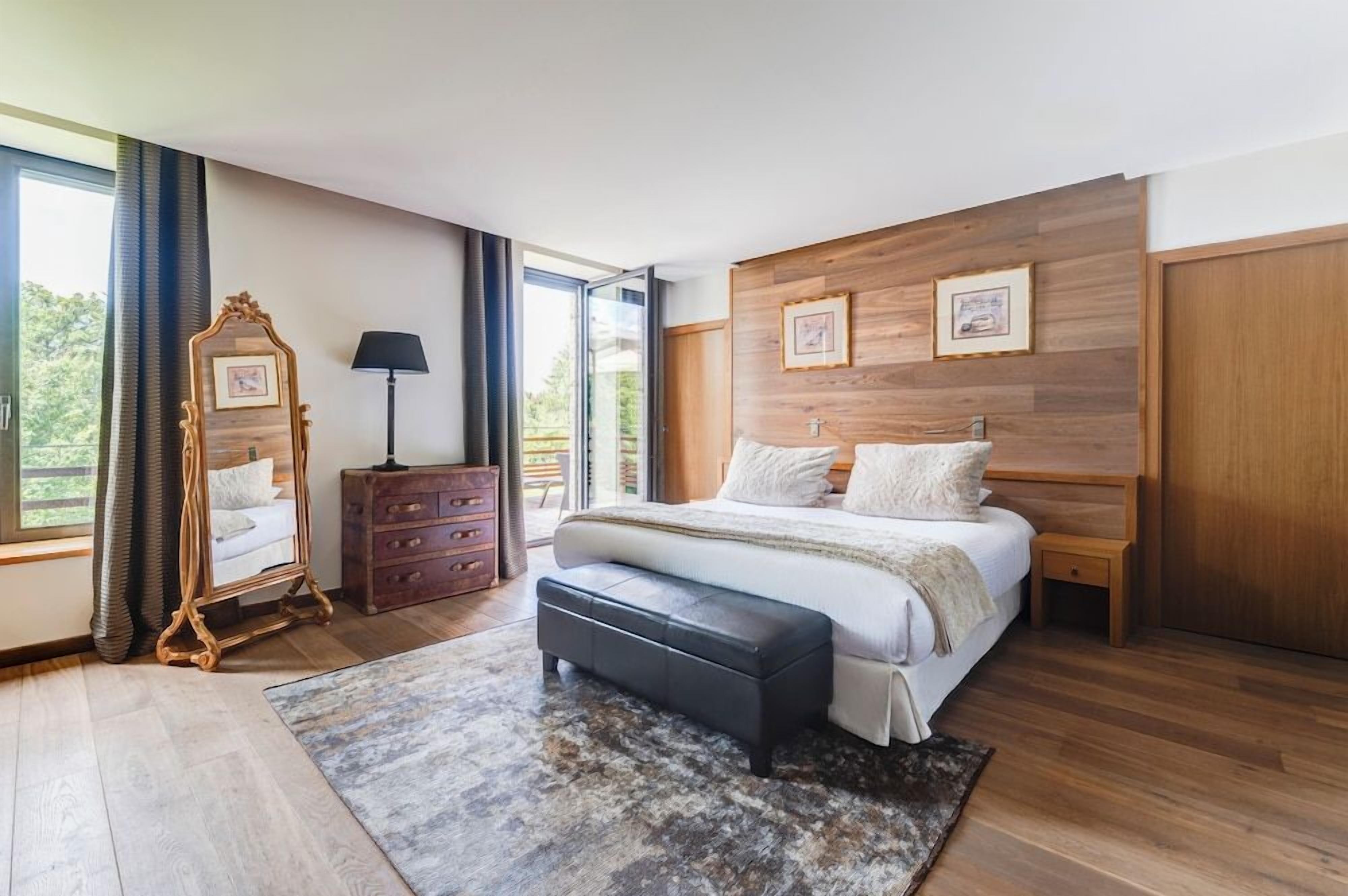 A bedroom with a large bed, a dresser, a mirror, and a window.