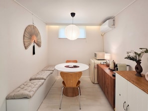 A compact kitchen with a round dining table, a built-in bench, and a hanging decorative fan. - Soyo Home Jongno : 1-bedroom house for 3 guests (Seoul)