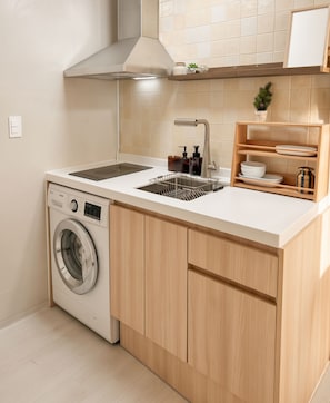 A compact kitchen with a built-in washing machine, a sink with a modern faucet, and wooden cabinetry. - Soyo Home Jongno : 1-bedroom house for 3 guests (Seoul)