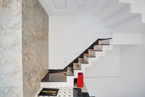 Una escalera moderna con una pared de mármol en un lado y un suelo estampado.