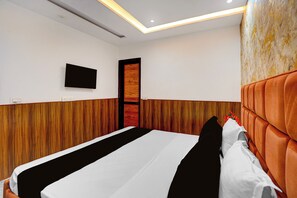 A hotel room with a bed, a flat-screen TV mounted on the wall, and a wooden door.