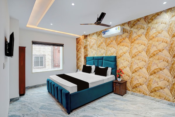 A modern bedroom with a large bed, a ceiling fan, an air conditioning unit, and a window with a view of a building outside.