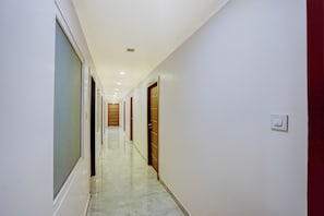 A long, narrow hallway with doors on both sides, leading to a room at the end. - Townhouse Oak Prayagraj Bus Terminal (Prayagraj)