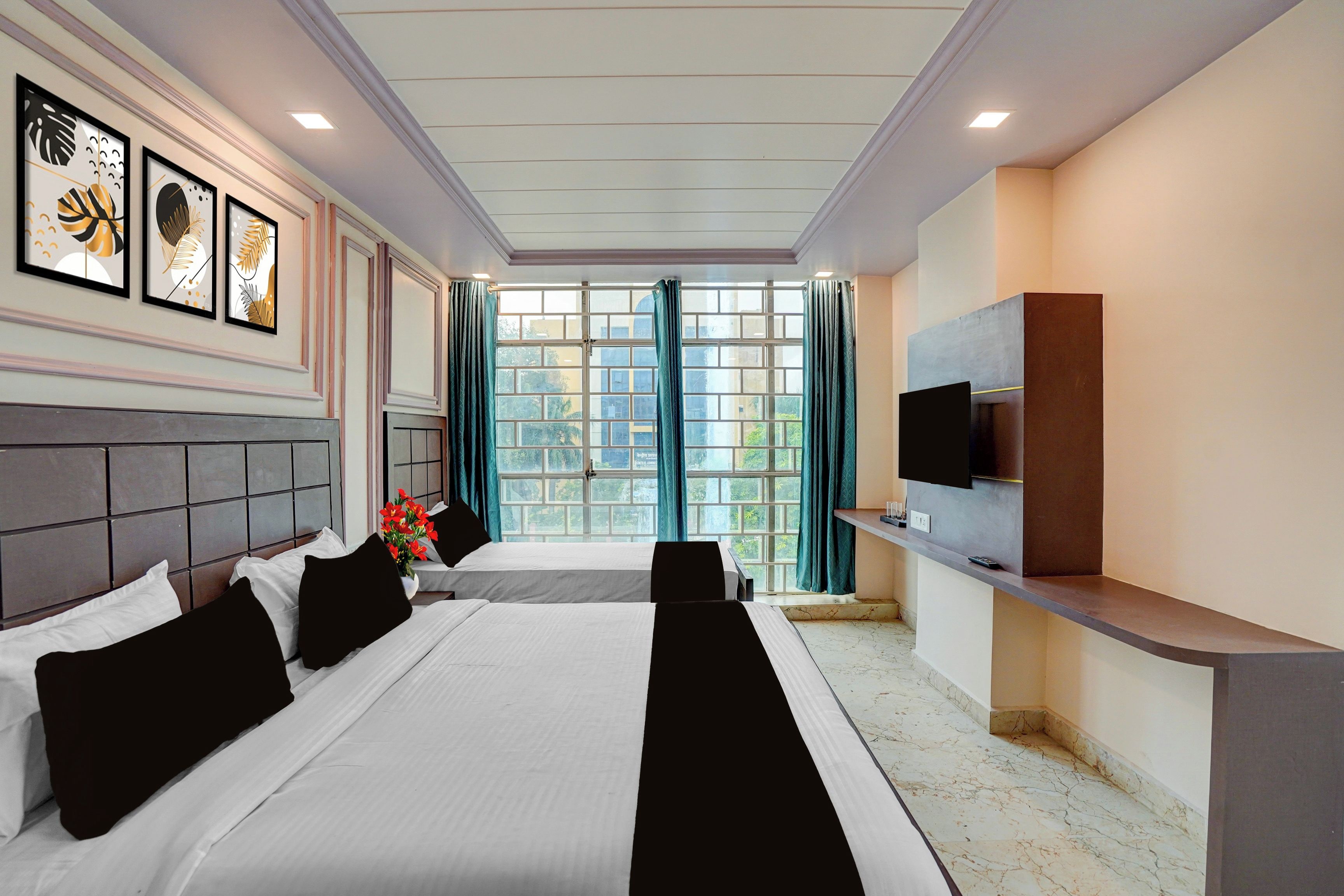 A hotel room with a large bed, a flat-screen TV, a window with curtains, and artwork on the wall.
